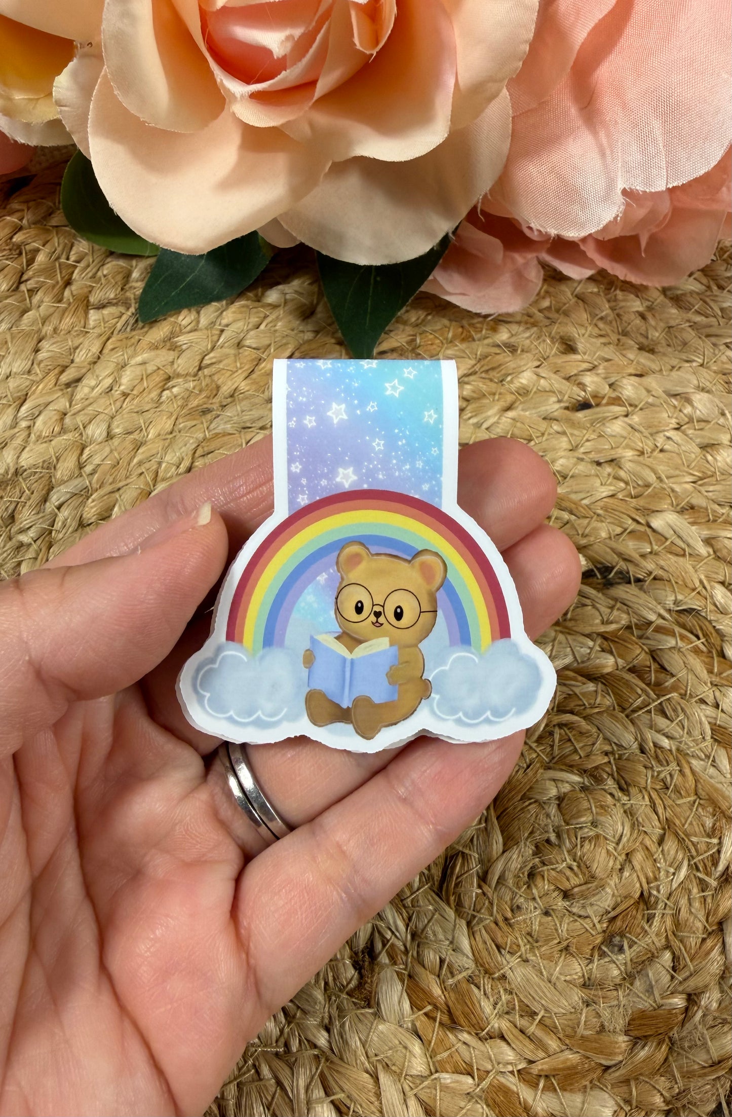 Rainbow magnetic bookmark held in hand to show its size and colorful rainbow design.
