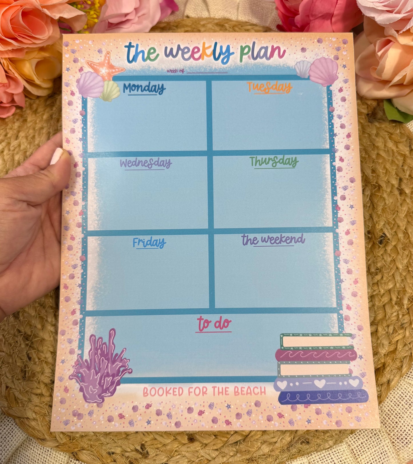 Beach Booked Weekly Planner held in hand to show its size and design.