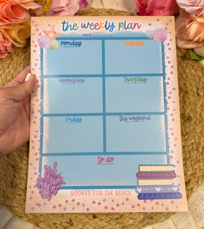 Beach Booked Weekly Planner held in hand to show its size and design.