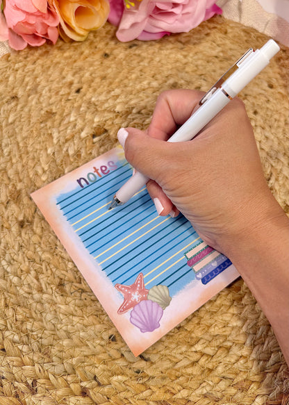 Beach Books Notepad held in hand with a pen to show its size and writing space.