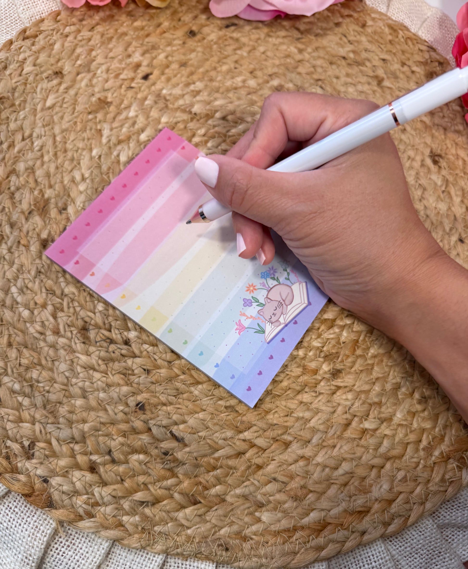 Rainbow Sleepy Kitty Notepad held in hand with a pen to show its size and writing space.