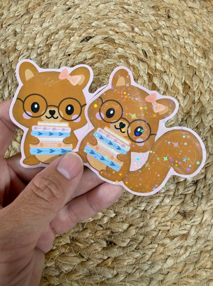 Storybook Squirrel Vinyl Sticker shown in Vinyl Glossy and Vinyl Star Holographic finishes held by hand.